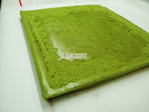 要捲的時候，正面鋪一張白報紙，翻面後一樣放在涼架上，將底部的烘焙布撕下來後，移開涼架，用刀子在前端割2條線，在尾端切斜口，會比較好捲