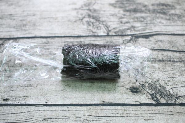 拉起保鮮膜把海苔往內捲緊飯壓實、捲成圓柱狀，靜置約5分鐘。