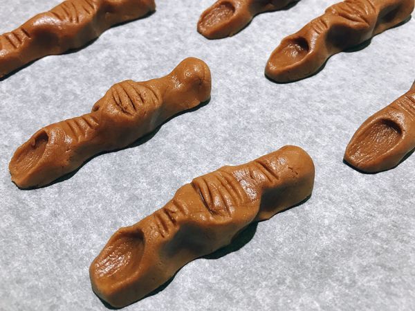 將冰過的麵糰切成10等分，搓揉成手指形狀，用湯匙在關節處壓下皺摺，用杏仁壓出指甲的凹槽。