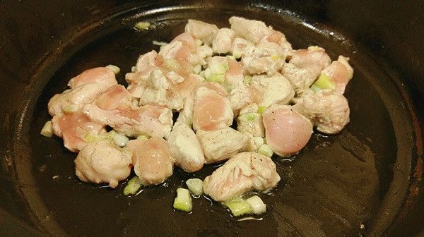 取炒鍋加入少許的油加熱後放入雞丁及蔥白拌炒