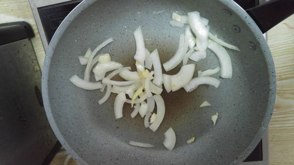 熱鍋加油，先爆香蒜頭，再加入洋蔥。