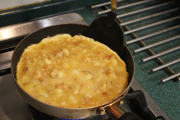 加熱另一只平底小鍋，放入一大匙橄欖油。中火加熱，將馬鈴薯蛋液倒入鍋內。這時不要再去拌它，只搖晃及震動平底鍋調整蛋餅的形狀即可。
加熱約3-5分鐘，邊緣的蛋已經開始凝固。
用鏟子或叉子確定一下蛋餅邊緣和鍋子是否很容易分離。