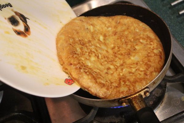 用大盤子，將蛋餅倒扣後，再將蛋餅倒回平底鍋中。