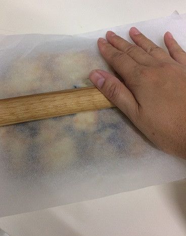 餅乾表面再蓋上一張烤盤紙，用擀麵棍稍微擀平