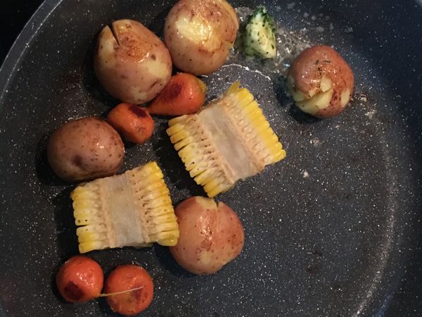 煎魚排的同時，可取另一鍋放少許橄欖油，將小蕃茄略煎並用少許鹽和胡椒粉調味即可。同時亦可將煮過的小馬玲薯、玉米和小紅蘿蔔一起略煎，小蕃茄先起鍋。如剛好手上有蒜味奶油抹醬者，可切ㄧ小塊入鍋，搖晃鍋子讓小馬玲薯、小紅蘿蔔和玉米都沾到溶化的奶油。如沒有,則可簡單用鹽和胡椒粉調味即可。