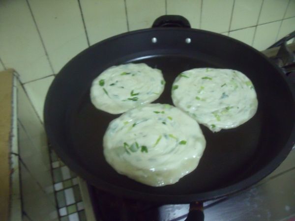 鍋中放少許的油,蔥油餅用手壓平,放入鍋中煎。