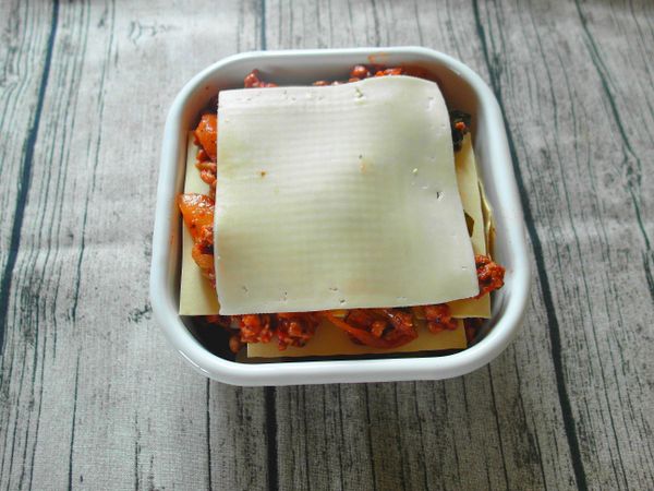 取一容器,依序放入千層麵,肉醬,番茄片,高達起司片,一層層疊起來