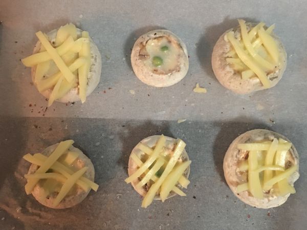 烤盤上鋪烘焙紙，將蘑菇放在上面，用少許的鹽和胡椒粉調味後倒入蛋液(確實每個蘑菇都放入青豆)，接著排上起司條，入烤箱烤15分鐘到起司呈金黃即可,出爐後擺盤並撒上切碎的巴西里葉，便可享用囉～