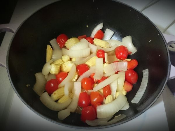 接著放入玉米筍（切段）、小番茄（對切）拌炒並加少許鹽調味，然後悶5分鐘。（中小火）