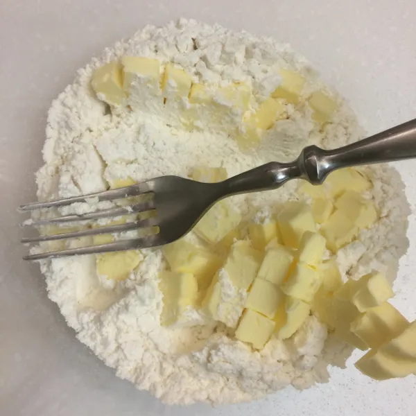 將奶油小方塊放入步驟一中，用叉子輕輕翻拌，使奶油都均勻裹上麵粉。