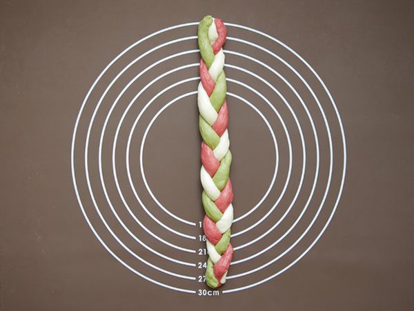 取三條不同顏色的長條狀麵團，以編辮子的方式將三色長條狀麵糰編成辮子狀。