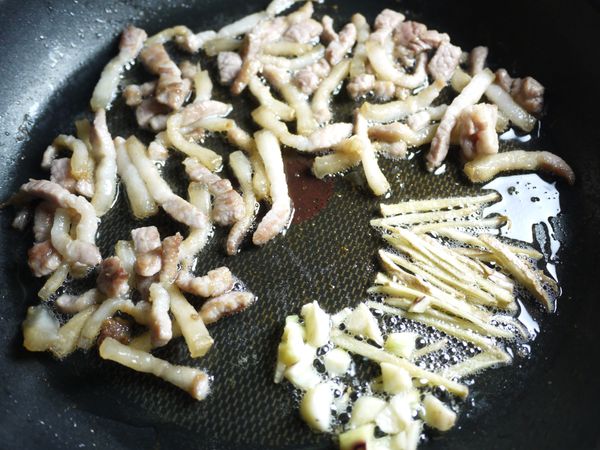 竹筍和豬肉切成絲狀。鍋中不放油直接下五花肉絲煎到油脂逼出,再下薑絲及蒜末爆香。(竹筍容易吃油及刮胃,所以一般炒竹筍油量會稍多,如果覺得爆出來的豬油過多可倒出來留著以後炒青菜)