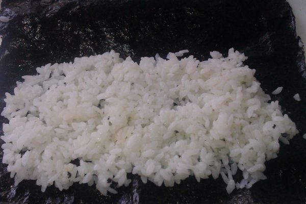 取出一片海苔片，再將白米飯鋪在上層，用湯匙輕輕壓平