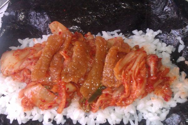 再將泡菜鋪在米飯上，接著鋪上豆棗