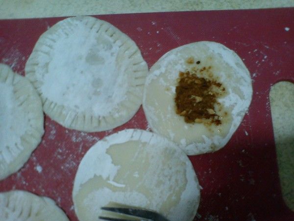 一匙糖餡鋪在水餃皮上、邊邊抹上一點水上面再蓋一張水餃皮，用叉子壓緊。