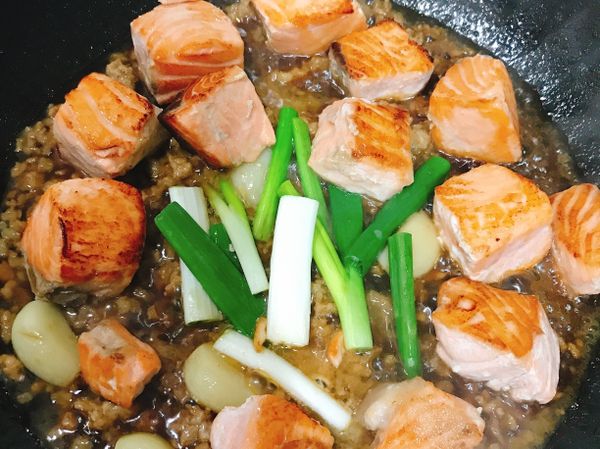 接著直接放入蒜頭至鍋中煎黃，在放入絞肉炒香後加入調味料（醬油、米酒、砂糖、烏醋，白胡椒粉、水）轉小火煮滾（約5-8分鍾），接著放入蔥段及鮭魚塊拌炒均勻，最後以太白粉水勾芡即完成！