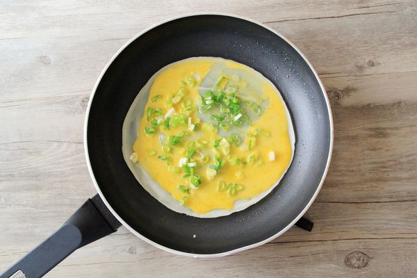 加入一顆打散的蛋液與少許蔥花，不用翻面直接小火慢煎，將餅皮外層煎脆。(1顆蛋配一片餅皮)