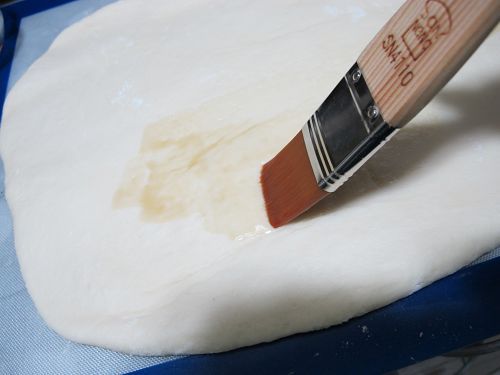 用刷子沾麻油在麵糰上。