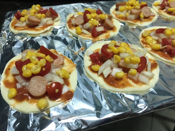 在水餃皮依據個人喜好塗抹一層蘑菇蕃茄醬，重口味的可以塗厚一點。依序放上已切好的洋蔥丁、蕃茄丁、德國脆腸與玉米粒。