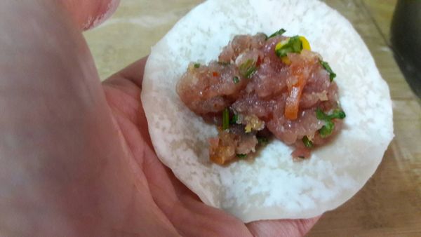 取一匙的肉餡放到餃子皮中央再包好