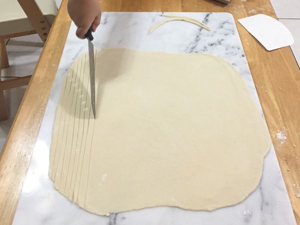 用刀將麵糰切成一條條粗細相當的麵條