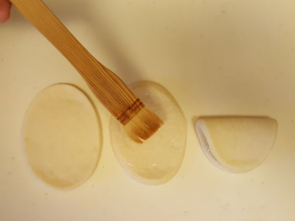 將壓好模的麵皮桿成橢圓形，翻面後塗上少許油再對摺