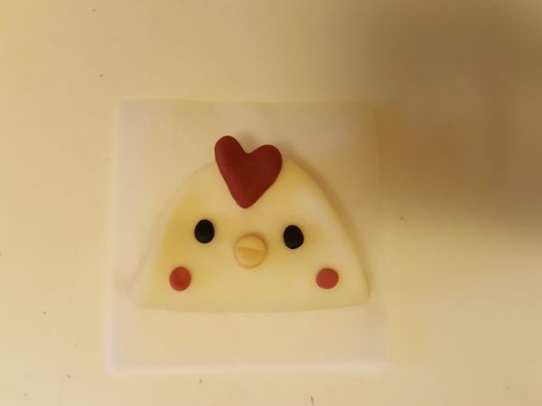 將其他有色麵團桿成片狀，用模型壓出所需形狀，並將各部位用手微調後沾水黏貼組合，放在防沾紙上