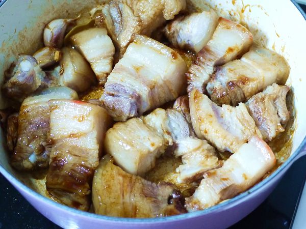 糖色炒出來後，放入蒜頭與薑片炒出香味，再放入先前煎好的豬肉塊炒至豬肉塊都裹上糖色