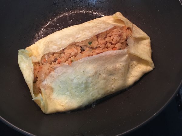 用鍋鏟將四邊折起定型後就關火,並用鍋鏟直向鏟起,再將蛋包飯翻放在盤子上, 吃時在蛋皮上淋上適量蕃茄醬做裝飾.
