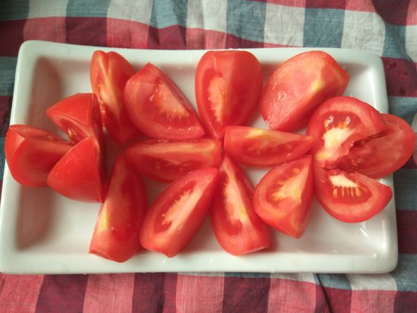 將牛蕃茄沖洗乾淨，先對切成二半，再視蕃茄大小半塊切成三等份或是4等份，將切好的牛蕃茄放到盤子裡。