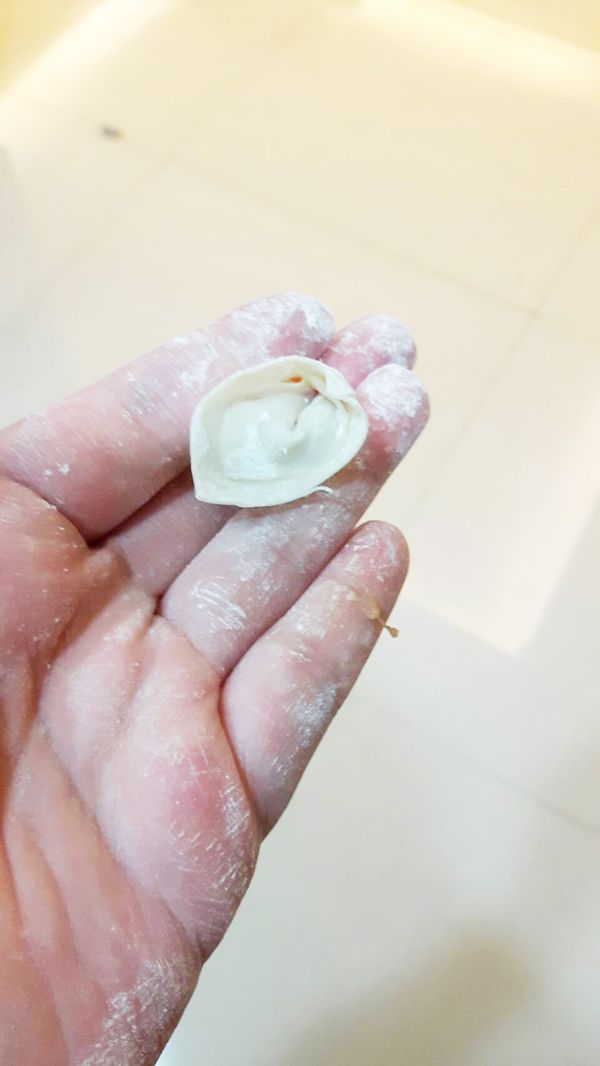 拿起１／４餛飩皮在手中擺成菱形，將餡料集中在下，上下點對折不須壓緊，再將左右角沾點水折起來黏緊（只須黏左右角即可）。