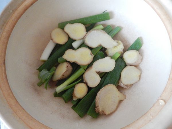 豬肉跑活水去腥味的時候，來切蔥段與薑片，將其平鋪在鍋底。