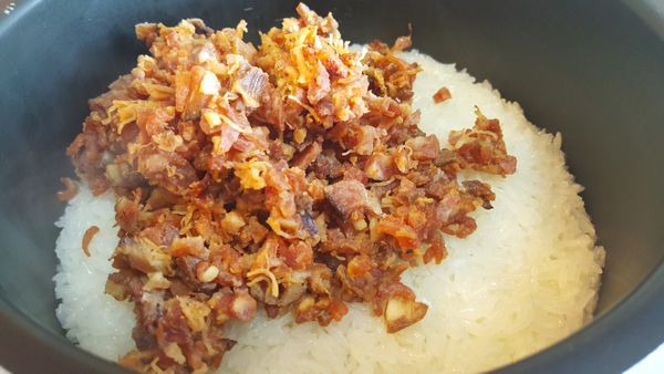 將電飯煲拿出，加入已炒好的臘味及鹽。