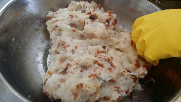 手戴手套，用手將糯米飯及臘味拌勻，再用輕力按壓成糯米糰。