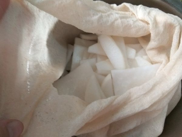 將處理過的白蘿蔔薄片倒入製作豆漿過濾用的袋子。