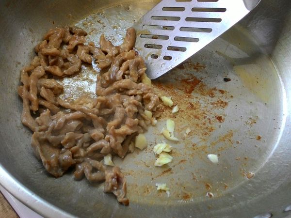 加入蒜頭碎齊炒，炒到肉的顏色變白色，就可以先取出備用。