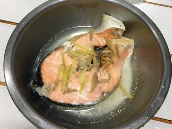 鮭魚片放上薑絲，置於電鍋內蒸煮（外鍋一杯水）