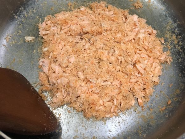 將蒸熟的鮭魚，去薑絲去魚刺，可用叉子將魚肉撥散，再入平底鍋，炒至鮭魚肉乾燥。