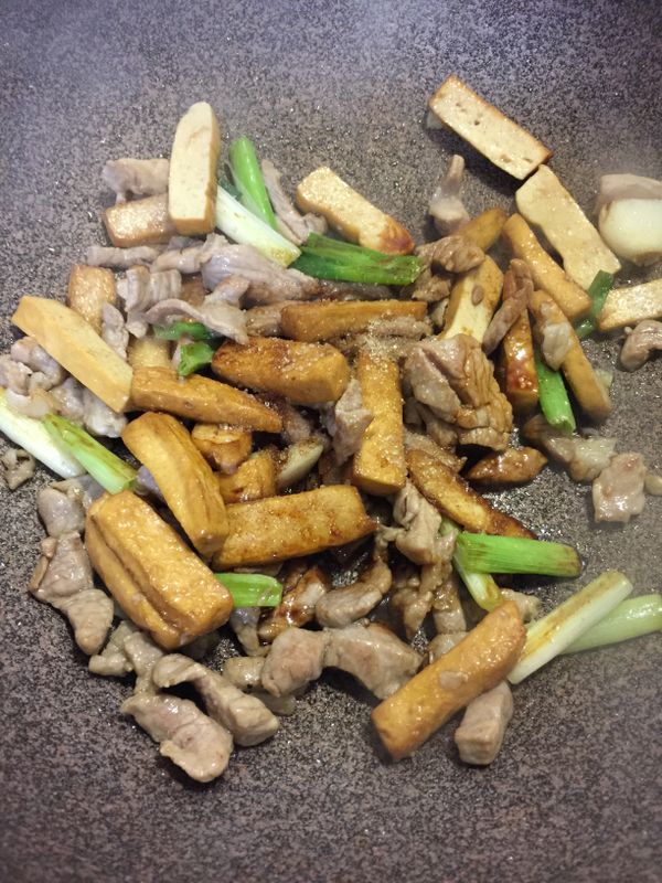豆干煎好直接加入肉絲、蒜末，蔥白段ㄧ起煸炒，肉絲6.7分熟即可