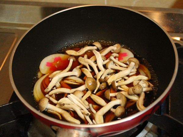 取一20公分平底鍋，倒入[醬汁]、洋蔥、鴻喜菇及魚板中大火燒滾