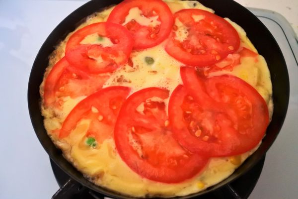 蛋液約半凝固鋪上番茄片再蓋上鍋蓋