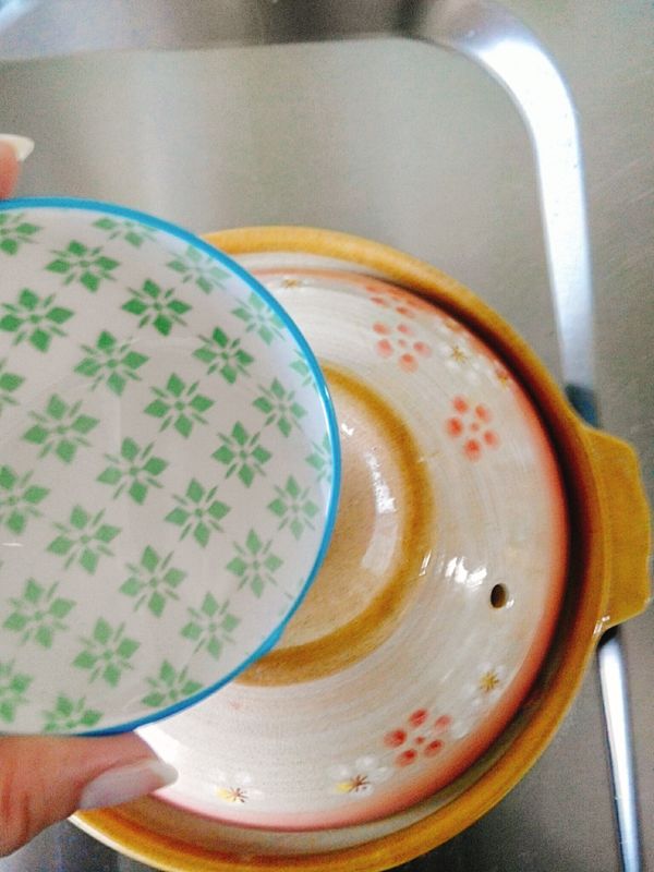 蓋上鍋蓋，沿著鍋蓋邊緣淋上米酒(紹興酒)，小火煮5分鐘左右，產生鍋巴，關火，放上香菜(蒜苗)，上桌。