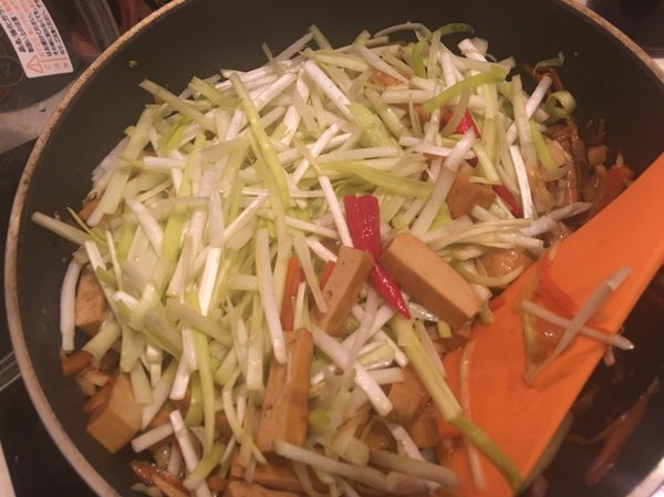 看見豆乾上色入味之後，把韭黃加進來，然後送它兩支小辣椒，與醬油、鹽巴大火熱炒。