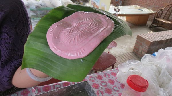 然後取一香蕉葉，將香蕉葉貼住龜模上的紅龜粿後輕敲3下，紅龜粿自然落下或輕輕沿著紅龜粿邊沿慢慢撥下。再將香蕉葉修剪成適當大小(一定要比紅龜粿大一些)。