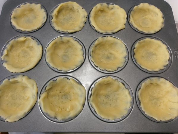 塔皮取出打開保鮮膜，上面再蓋一層保鮮膜，用擀麵棍將塔皮擀成約1塊錢的厚度，將塔皮放入塔模中