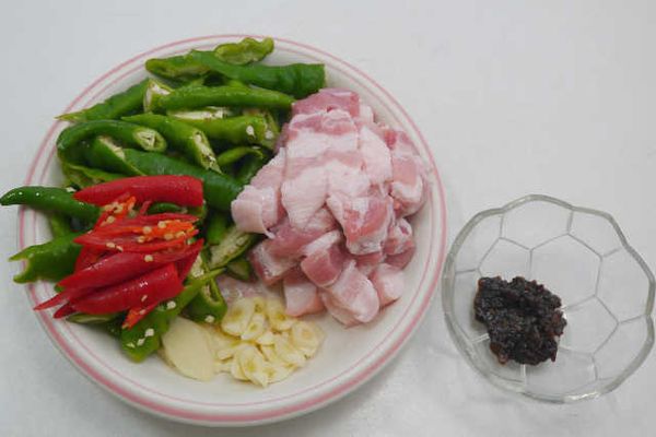 五花肉切成1公分條狀、糯米椒和辣椒切長滾刀、蒜頭切片、豆豉切碎備用。