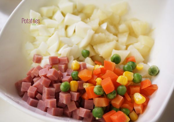 再將起先預留的馬鈴薯丁、三色豆、火腿丁及水煮蛋白丁加入。