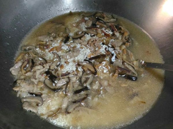 2.5杯水(我是用泡過香菇的香菇水)，加入米，拌炒一下稍稍煮沸，倒至電子鍋，起動煮飯