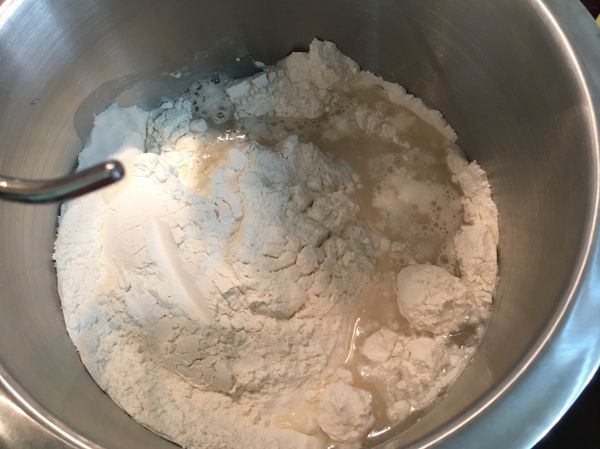 將麵粉、鹽、糖、酵母放到攪拌器內，冰水分三次倒入鋼盆內，充分攪拌