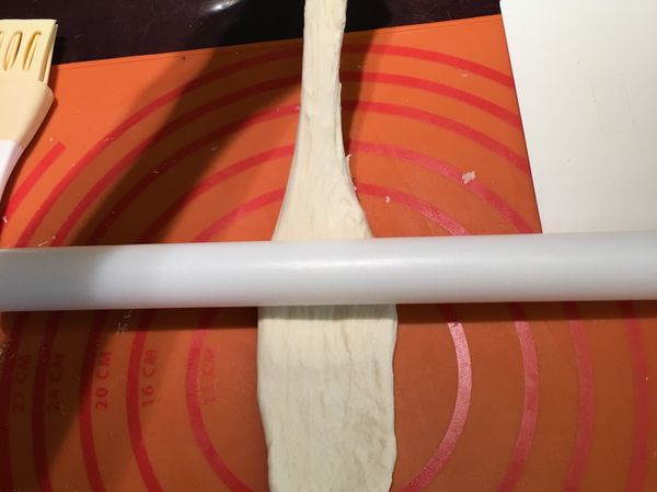 手拉著麵糰尖端，桿麵棍順著往後桿